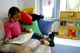 Young girl sits on couch and looks at a book
